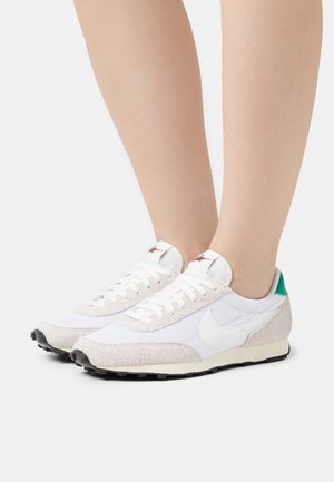 Chaussures de sport blanches avec extérieur en maille et suède, accent vert au talon et lacets blancs ; semelle texturée pour une meilleure adhérence.