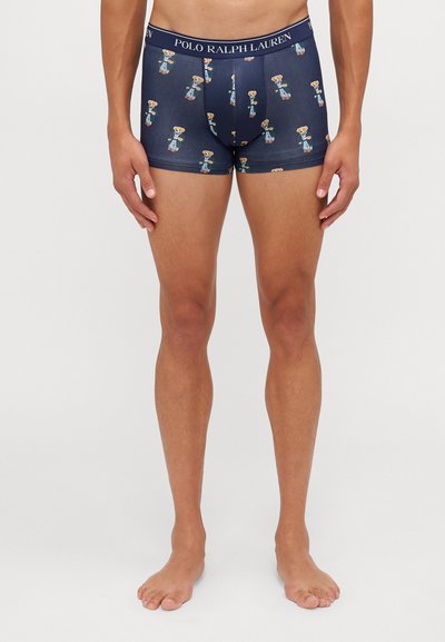 Boxers de cor azul marinho com padrão de urso em cartoon, feitos de tecido elástico com uma faixa sólida rotulada "POLO RALPH LAUREN."