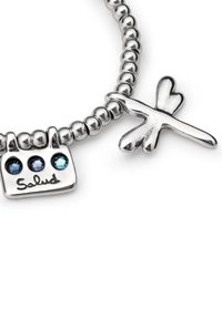 Pulsera de cuentas de plata que incluye un charm con la inscripción "Salud" y tres piedras de colores, junto a un colgante con forma de libélula.