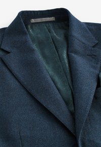 Marineblauer Wollblazer mit Reverskragen, einreihig und einem gemusterten, grünen Satinfutter. Verfügt über seitliche Taschen und saubere Nähdetails.