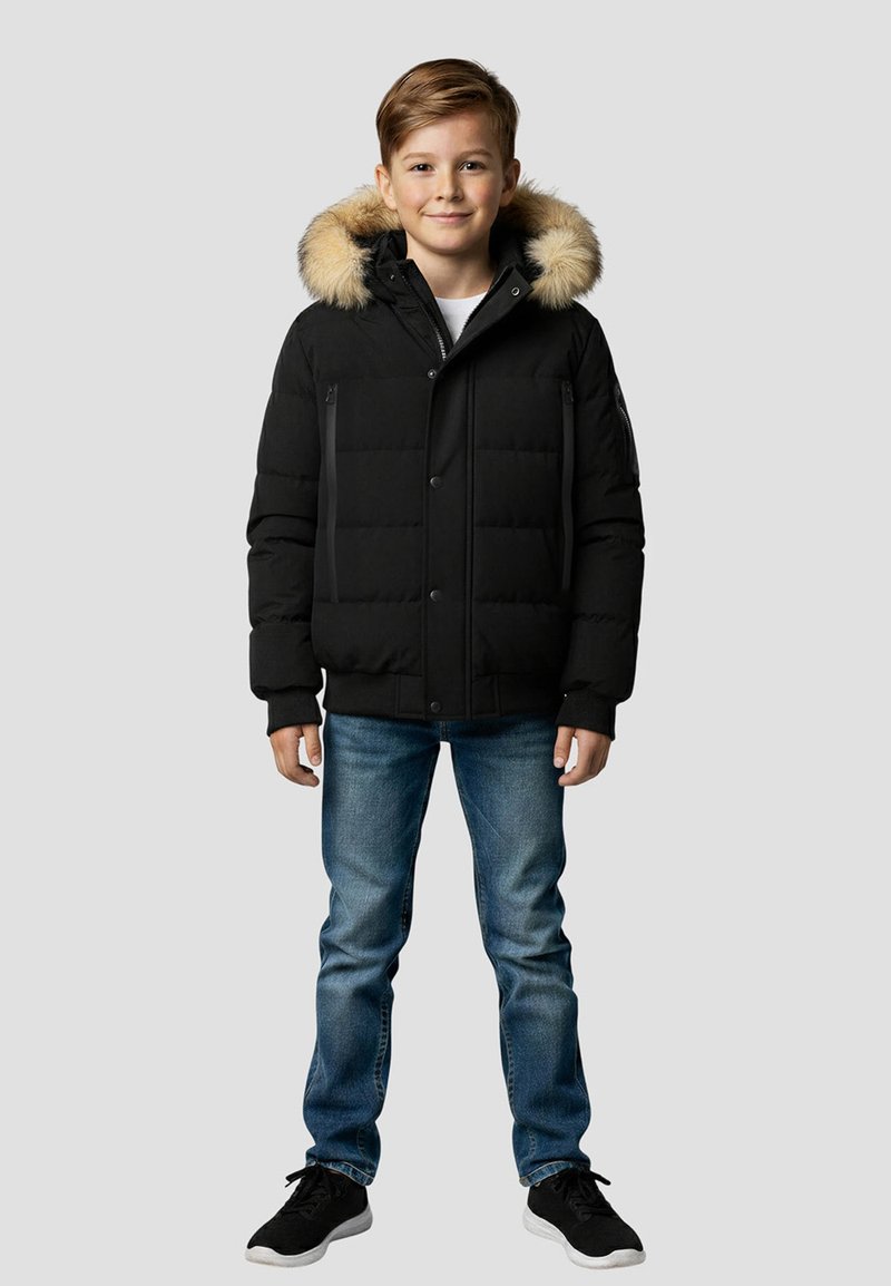 Sort polstret vinterjakke med pelsforet hætte, lynlåslommer og knaplukning. Båret med blå jeans og sorte sneakers.