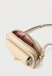 Μπεζ δερμάτινη τσάντα χιαστί με χρυσές μεταλλικές λεπτομέρειες, κλείσιμο με φερμουάρ, υφή στο φινίρισμα και αντίθετο χρώμα στο εσωτερικό. Περιλαμβάνει μπροστινή θήκη.