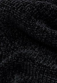 Coperta nera con texture, realizzata in un morbido tessuto peloso con un motivo ondulato. Il materiale appare soffice e lussuoso.