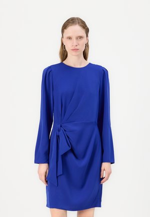 Vestido azul con mangas largas, escote redondo y un detalle de nudo en la cintura. Hecho de una tela suave con una silueta drapeada.