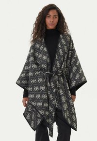 Kimono in bianco e nero con motivo a fantasia, stile avvolgente e cintura a cravatta, caratterizzato da un design geometrico e maniche ampie, realizzato in un tessuto morbido.