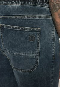 Vaqueros de denim en un lavado oscuro, con un bolsillo trasero con un logo en relieve, costuras en contraste y una cinturilla texturizada.