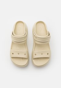 Beige sandals with a smooth, matte finish and adjustable strap. Features ventilation holes and a contoured footbed for comfort.