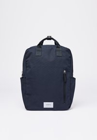 Purjehdusreppu, joka on valmistettu kestävästä kankaasta, jossa on kaksi yläkahvaa, etupuolen vetoketjutasku ja sivutasku. Mukana logo-tarra.