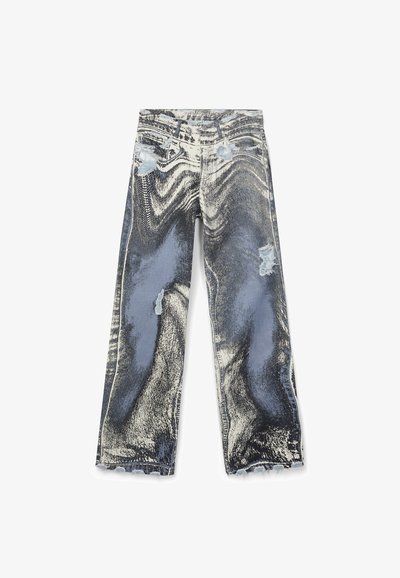 Jean en denim avec un motif déformé en noir et blanc, des patches bleu clair et des détails usés sur les cuisses et les ourlets.