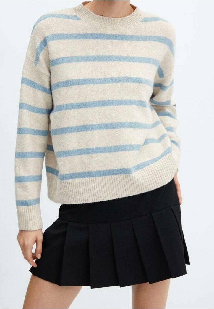 Maglione crema con righe orizzontali blu, colletto e orlo a coste. Abbinato a una gonna nera plissettata, la texture del tessuto appare morbida e accogliente.