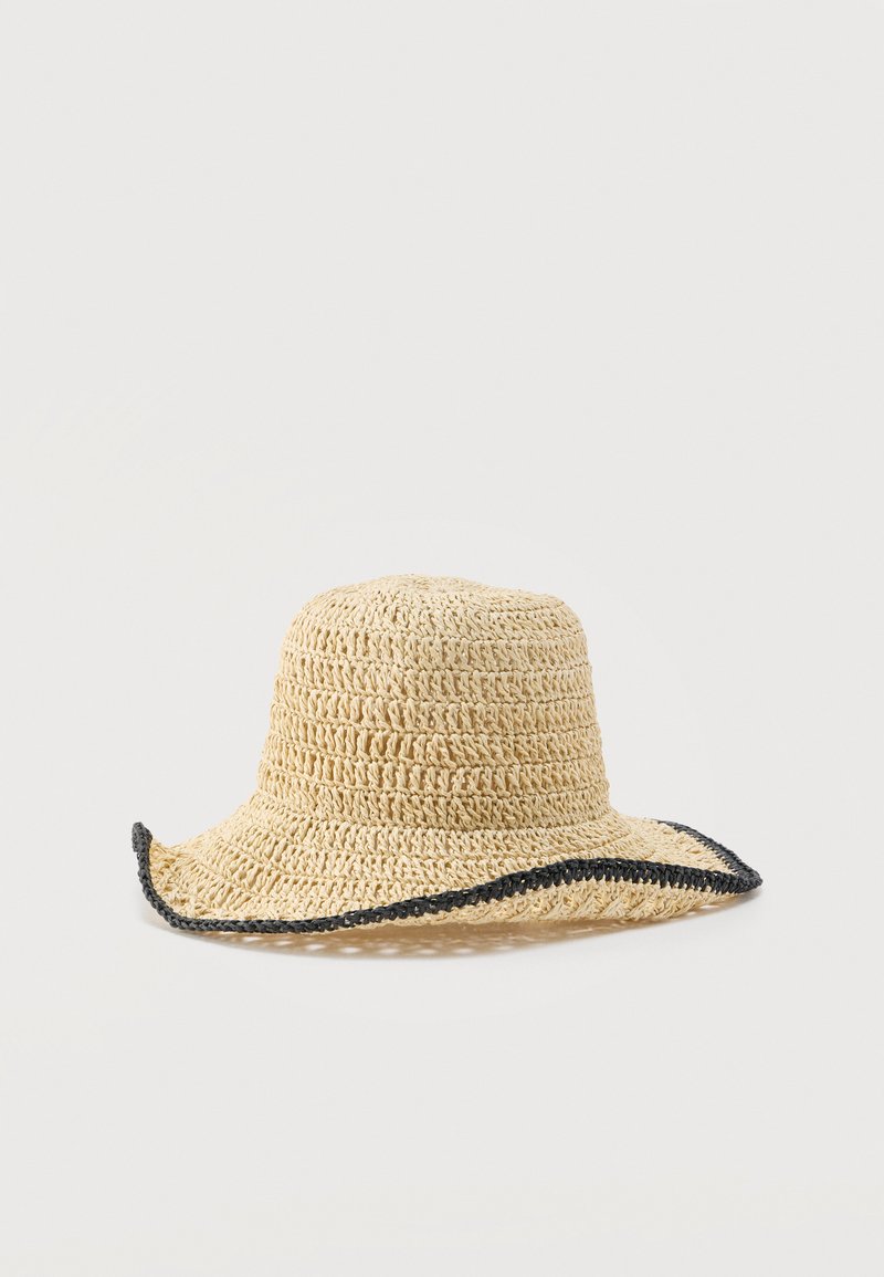Chapeau de soleil en paille tissée beige avec un large bord souple bordé de noir, présenté sur un fond clair uni.