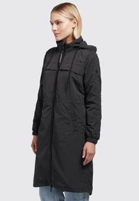 Black hooded jacket, long length, made from a smooth, lightweight material. Features front pockets, zip closure, and drawstring adjustments.
