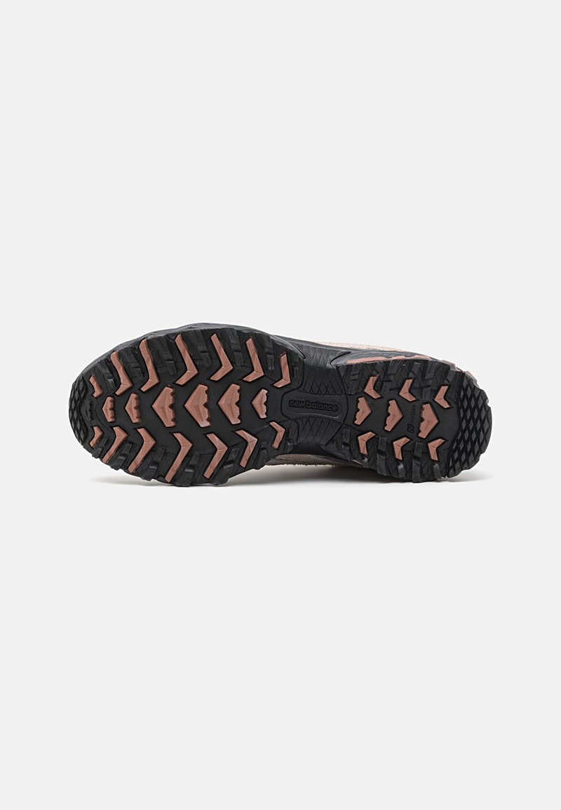 Semelle en caoutchouc noir avec des profondeurs de crampons et des accents roses. Matériau durable avec une surface texturée conçue pour offrir une traction sur divers terrains.