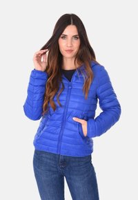 Giacca puffer blu con design trapuntato orizzontale, chiusura frontale con zip, due tasche laterali e una texture liscia e lucida.