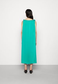 Langes, ärmelloses Kleid aus lebhaftem türkisfarbenem Stoff. Verfügt über eine lockere Silhouette, gerafften Ausschnitt und Bänder an den Schultern.