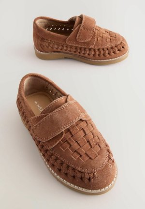 Chaussures en daim marron avec une tige en tissage et bout fermé. Dotées d'une sangle Velcro et de coutures blanches contrastées le long de la semelle.