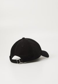 Black corduroy cap with a curved brim, textured fabric, and adjustable metal buckle at the back, featuring six ventilation holes.