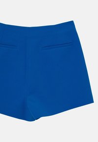 Pantaloni corti blu con una texture liscia, vestibilità su misura e due tasche posteriori. Il design è semplice con linee pulite e orlo dritto.