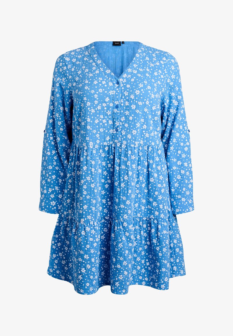 Mėlyna suknelė su baltu gėlių raštu, V formos iškirpte, sagų užsegimu, ilgomis rankovėmis ir sluoksniuotu raukiniu apatinėje dalyje. Pagaminta iš tekstūruotos medžiagos.