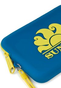 Estuche azul de silicona con cremallera que presenta un logo de sol amarillo, tirador de cremallera amarillo y un acabado texturizado. Forma compacta y redondeada con detalles de acento.