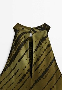 Mouwloze groene jurk met hoge kraag, keyhole rugdetail en zwarte abstracte patronen. Gemaakt van een gladde, glanzende stof.