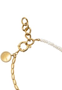 Pulsera de cadena de oro con eslabones de metal texturizados y una serie de pequeñas perlas blancas. Presenta un charm redondo grabado con el nombre de la marca.