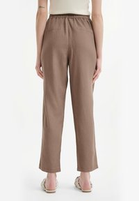 Pantalon marron en tissu léger et respirant, coupe décontractée, taille élastique et deux poches arrière ; coupe droite.
