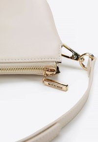 Beige kožená kabelka s texturovaným povrchem, zlatými kovovými prvky, zipovým uzavřením a štítkem s nápisem "WITTCHEN." Obsahuje odnímatelný popruh.
