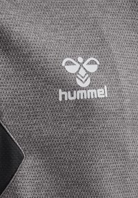 Gråt tekstureret stof med hvidt hummel-logo, der viser en stiliseret humlebi over mærkenavnet.