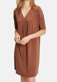 Brun V-ringad klänning med korta ärmar, löst snitt, mjukt material, plisserad detalj vid bröstet, når ovanför knäet.