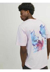 T-shirt rosa chiaro a maniche corte con una grafica astratta multicolore sul retro, completa di testo e dettagli intricati.