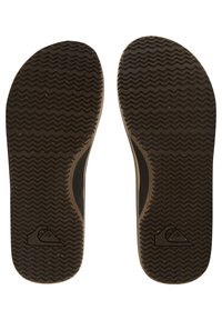 Brune gummisåler med bølgete mønster og en logo. Teksturert overflate for godt grep, formet for å passe standard fottøy.