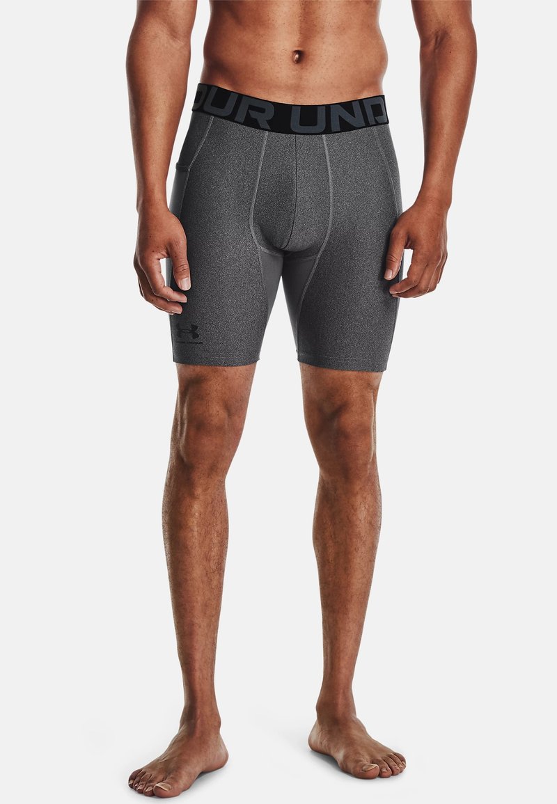 Shorts de sport ajustés gris avec une ceinture élastique noire, arborant un logo et une texture lisse. Design mi-cuisse.