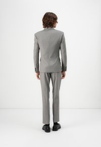 Grå rutig kostym med en skräddarsydd design, som har en notch-krage och två bakventiler. Stylerad med svarta skor och slim fit byxor.