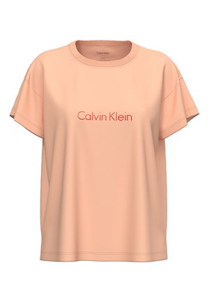 Brzoskwiniowy t-shirt z krótkim rękawem, z okrągłym dekoltem i czerwonym wyszywanym logo „Calvin Klein” na środku z przodu.