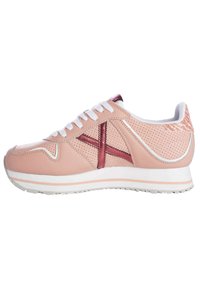 Sneaker rosa chiaro realizzato in materiale traspirante con perforazioni, dettagli in contrasto color bordeaux, lacci bianchi e suola in gomma con un leggero tacco.