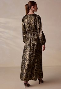 Langes Kleid mit Leopardenmuster aus gold-schwarzem Satin, mit geraffter Taille, langen Ärmeln und glatter Textur.