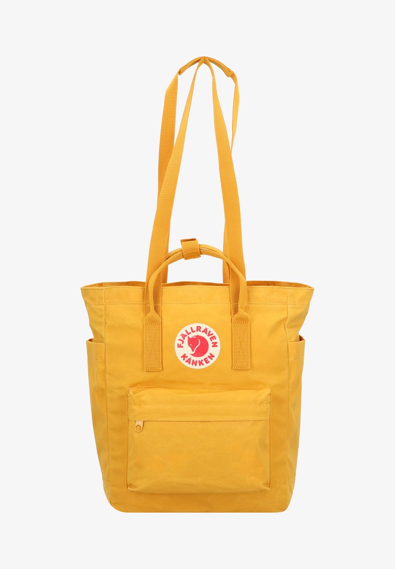 Gul tote taske lavet af holdbart stof, med to korte håndtag, lange remme, en frontlomme med lynlås og et rundt logo.