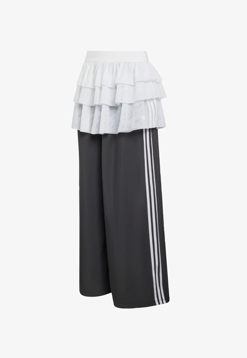 Athletiske bukser i mørkegrå med tre hvide striber på siden, toppet med et lagdelt flæset hvidt lag. Blødt stof, bred pasform.