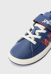 Plave sintetičke tenisice s bijelim vezicama i crvenim uzorkom paučine. Imaju remen na čičak i teksturiranu gumenu potplatu.