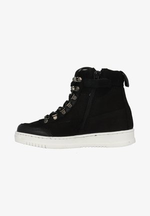 Bottines noires en suède et cuir, avec des accessoires en métal, une fermeture éclair sur le côté et une semelle en caoutchouc blanche avec un design texturé.