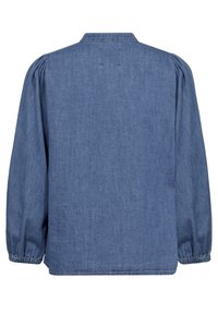 Denimskjorta i ljusblått med ryggsöm, samlade puffärmar och elastiska manschetter. Texturerat tyg med synlig sömnadsdetalj.