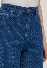 Hochtaillierte blaue Jeans aus Denim mit einem strukturierten Muster, fünf Taschen, Metallknopfverschluss und subtilen Steppdetails.