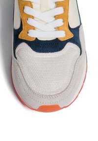 Sneaker con una punta in rete grigia, accenti in suede blu navy e beige, lacci bianchi e una suola in gomma arancione. Presenta un design arrotondato e sportivo.