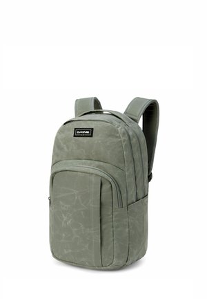 Mochila verde de Dakine con correas de hombro acolchadas, bolsillo frontal con cremallera y compartimento principal con cremallera, de pie sobre un fondo blanco.