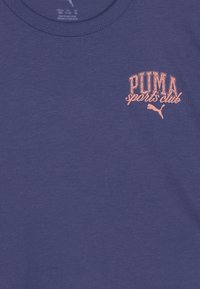 Mørkeblå bomull T-skjorte med en rosa PUMA sportsklubb-logo på øvre venstre side. Rund hals og jevn tekstur. Enkelt design.