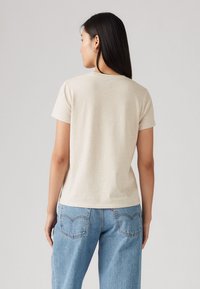 Beige bomulls t-skjorte med korte ermer, rund halslinje og avslappet passform, kombinert med lyseblå rette jeans.
