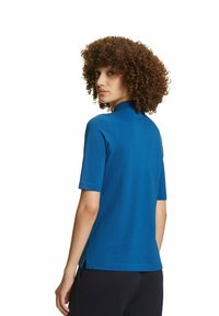 Korte mouwen blauwe polo shirt gemaakt van gladde stof, met een omgeslagen kraag en zijsplitten aan de zoom.