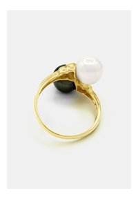 Bague en or avec un bandeau texturé, ornée d'une grande perle blanche et d'une pierre noire, mettant en valeur un schéma de couleurs contrasté et des surfaces lisses.