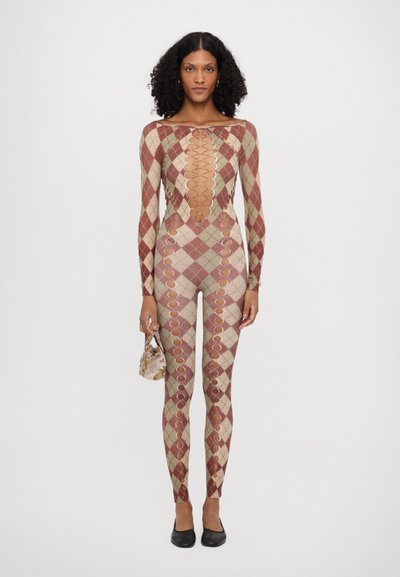 Mønstret jumpsuit i rød, beige og brun med diamantformer. Har udskårne detaljer langs sømmene og en dyb halsudskæring. Holder en lille taske.